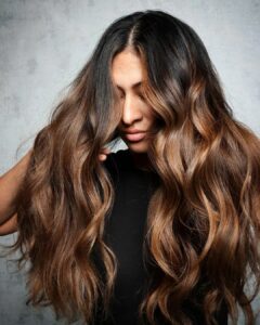 woman with dark roots and stunning caramel balayage